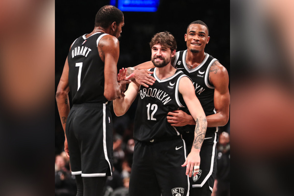 Brooklyn Nets forward Joe Harris (c.) celebrates with forwards Kevin Durant (l.) and Nic Claxton.