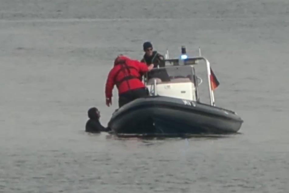 Die Polizei musste am Sonntag eine Frau (l.) aufhalten, die offenbar zum gestrandeten Wal schwimmen wollte.