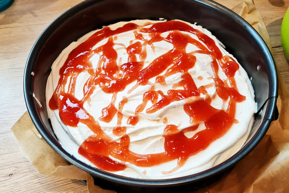 Wer ein säuerliches Obstaroma hinzufügen möchte, kann erwärmte Marmelade auf die Creme laufen lassen.