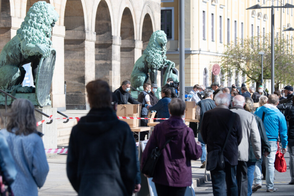 Mitarbeiter der Stadt Dresden verteilen vor dem Rathaus Mundschutzmasken.