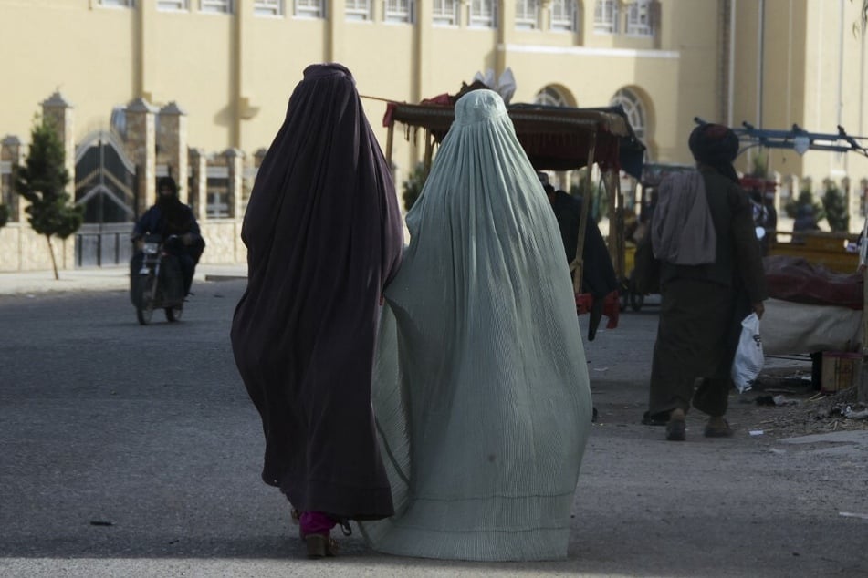 Burqa-clad women walk along a street in Kandahar, Afghanistan.