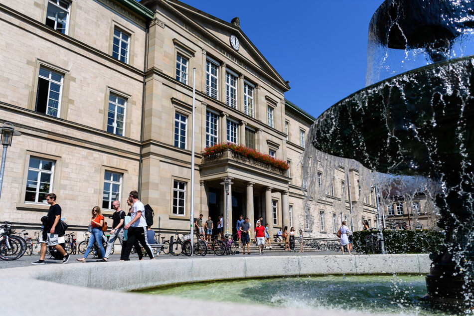 Studentinnen und Studenten laufen vor der Neuen Aula der Universität Tübingen an einem Brunnen vorbei. (Archivbild)