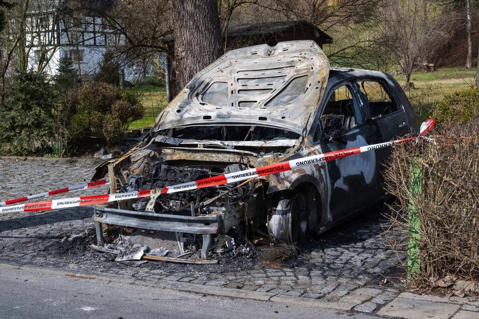 Der VW Golf steht ausgebrannt hinter einem Absperrband.