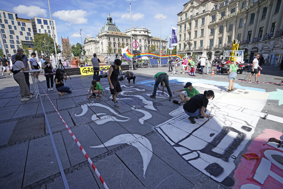 Mitglieder verschiedener Umweltschutzorganisationen bemalen am Rande einer Podiumdiskussion den Boden am Karlsplatz.