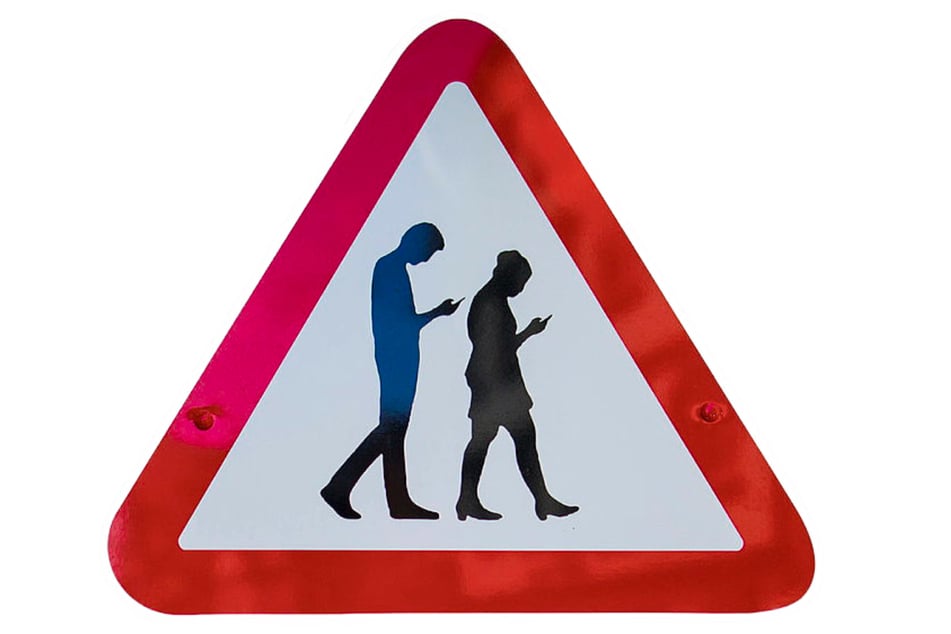 Der Kopf nach unten geneigt, der Blick auf dem Handy eingefroren: So sieht man viele Menschen auf der Straße laufen. (Symbolbild)