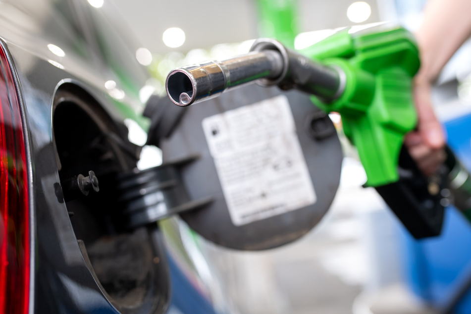 Eine Frau hält an einer Tankstelle an einer Zapfsäule eine Zapfpistole in der Hand und betankt ein Auto. (Symbolbild)