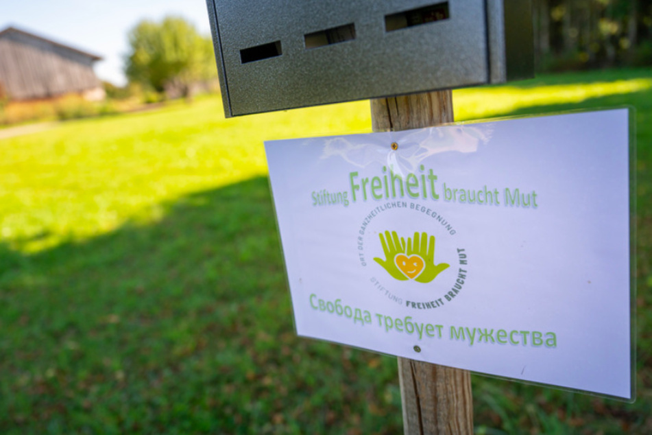 Ein Schild mit der Aufschrift "Stiftung Freiheit braucht Mut - Ort der ganzheitlichen Begegnung" hängt vor einem Gebäude am Ortsrand von Schechen.