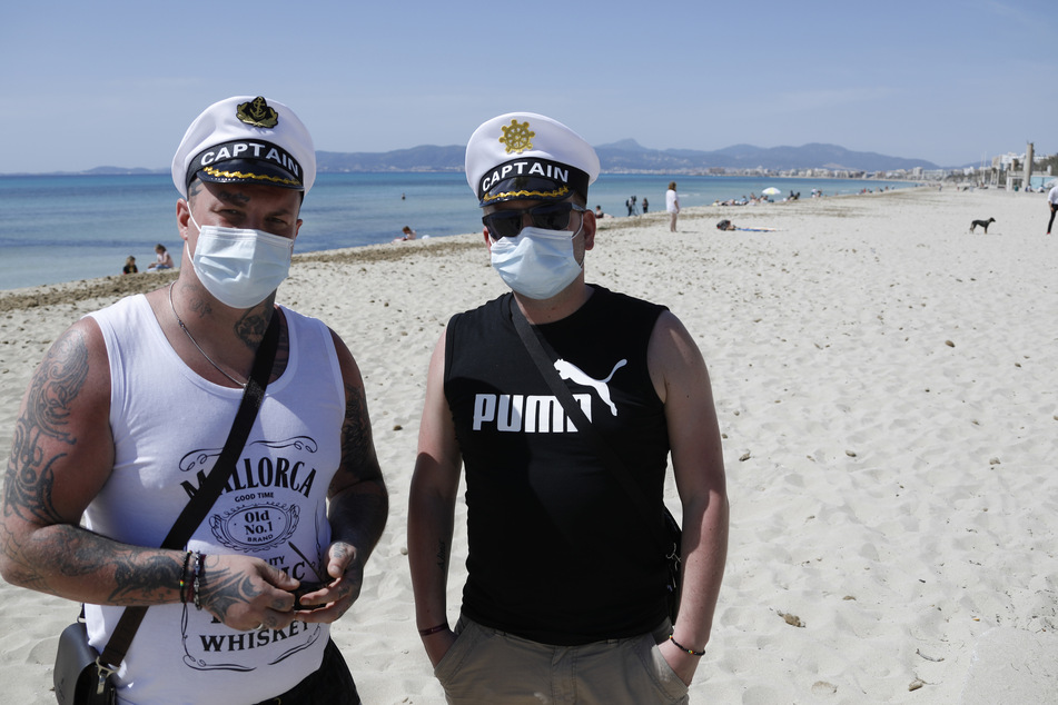 Dominik and Angelo aus Attendorn tragen medizinische Masken bei ihrem Aufenthalt am Strand von El Arenal.