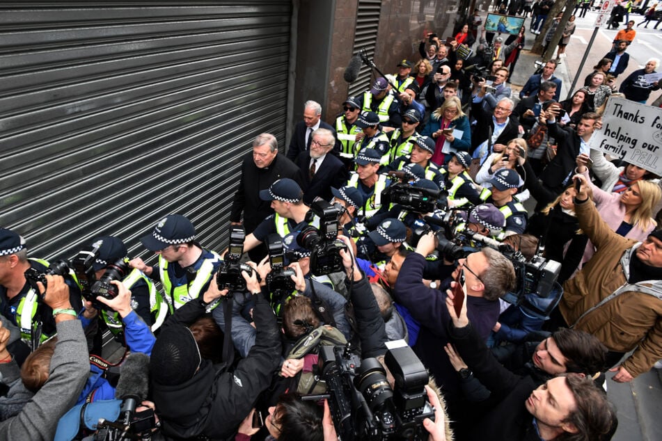 Juli 2017: George Pell verlässt eskortiert von Polizisten und umzingelt von Medienvertretern das Gericht, den Melbourne Magistrates Court.