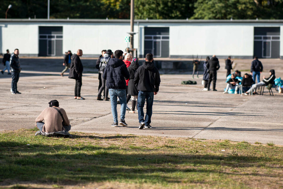 Asylsuchende laufen in der Erstaufnahmeeinrichtung Eisenhüttenstadt über einen Platz. Seit August ist die Zahl der Flüchtlinge, die über die Belarus-Route illegal nach Deutschland einreisen, sprunghaft angestiegen.