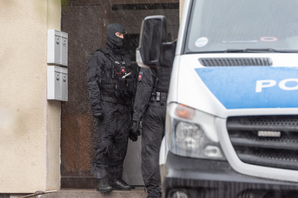 Beamte stehen vor einem der durchsuchten Objekte.