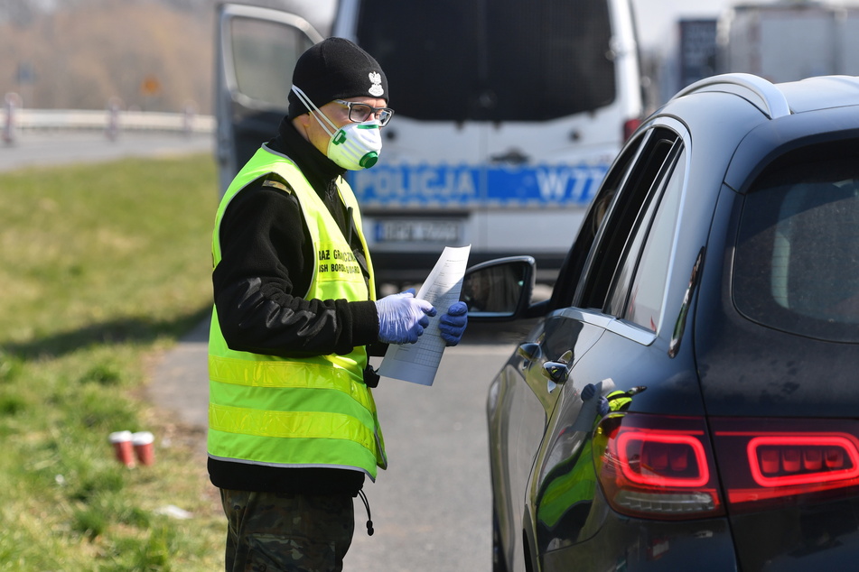 Polnische Grenzschutzbeamte mit Mundschutzmasken führen Kontrollen während der Coronavirus-Pandemie an der deutsch-polnischen Grenze durch.v