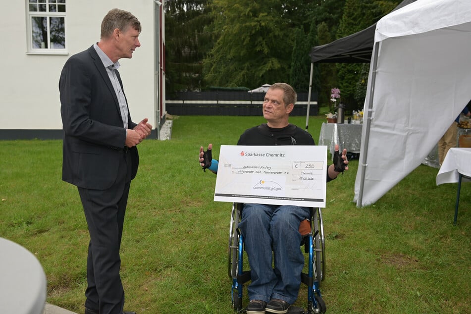 Uwe Bauch (56, l.), Vorstandsvorsitzender von "community4you", übergibt Sascha Stoltze (48) vom Verein Miteinander statt Gegeneinander einen Spendencheck.