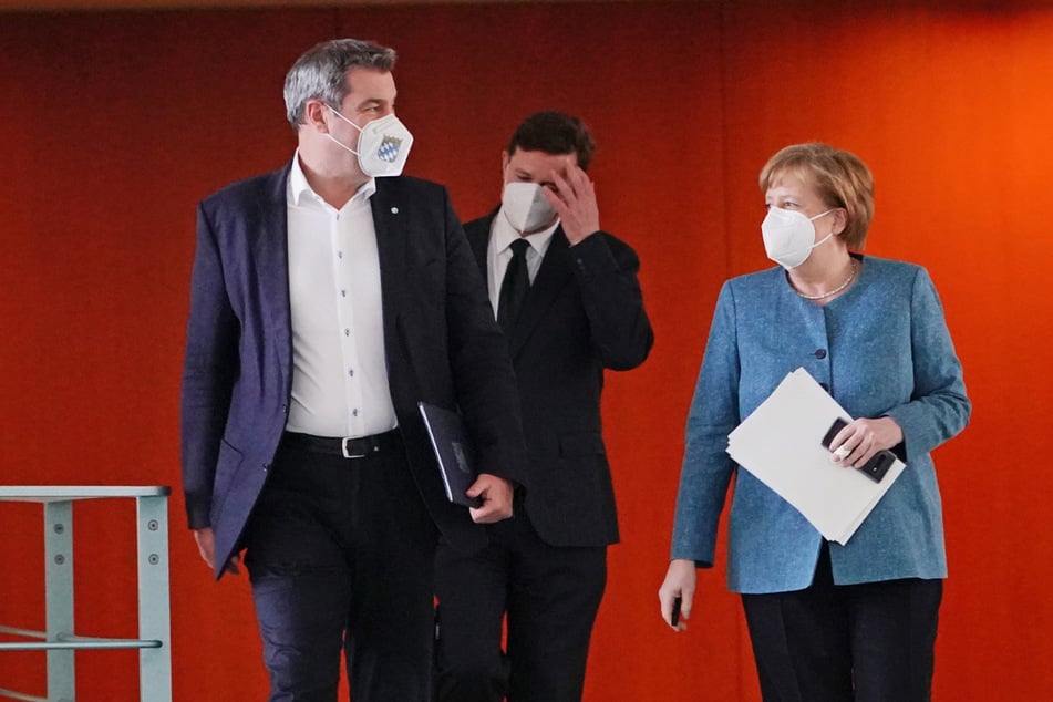 Bundeskanzlerin Angela Merkel (CDU) kommt neben Markus Söder (CSU, l), Ministerpräsident von Bayern und CSU-Vorsitzender, Zu der Pressekonferenz nach dem Impfgipfel im Kanzleramt.