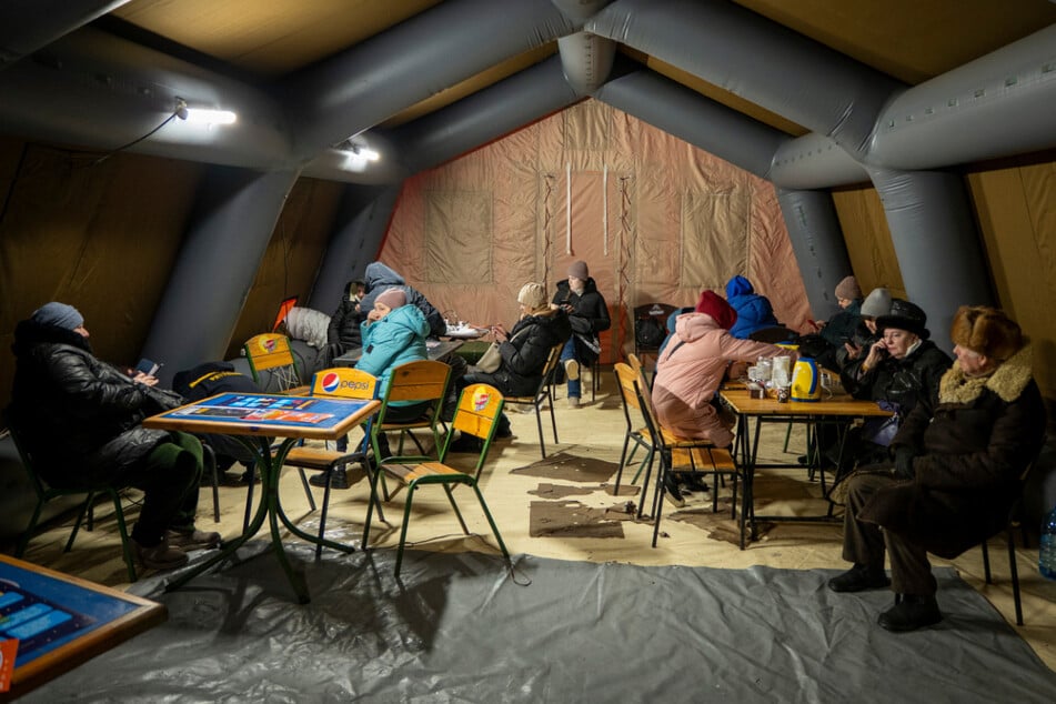 Menschen wärmen sich und laden ihre Akkus in einem Zelt auf, das der Rettungsdienst nach den russischen Luftangriffen auf den ukrainischen Energiesektor aufgestellt hat.
