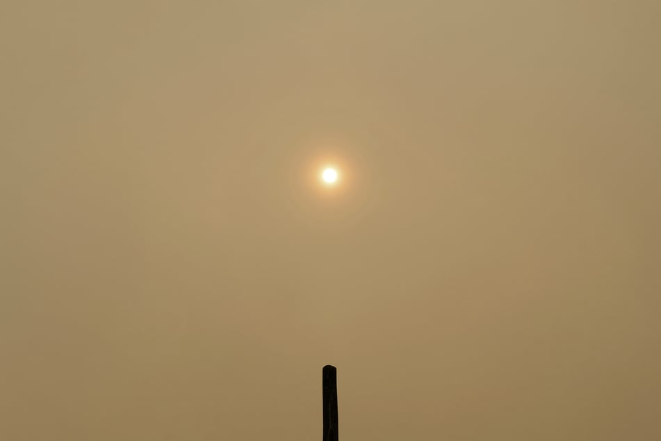 Die durch den Waldbrand ausgelösten, dichten Rauchwolken vernebeln den Himmel und tauchen die Welt unter ihnen in ein düsteres, orangenes Licht.