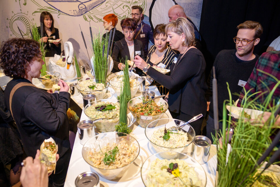 Gäste und Jury kosten sich beim "Familientreffen der Gastronomen" durch die Kartoffelsalate.