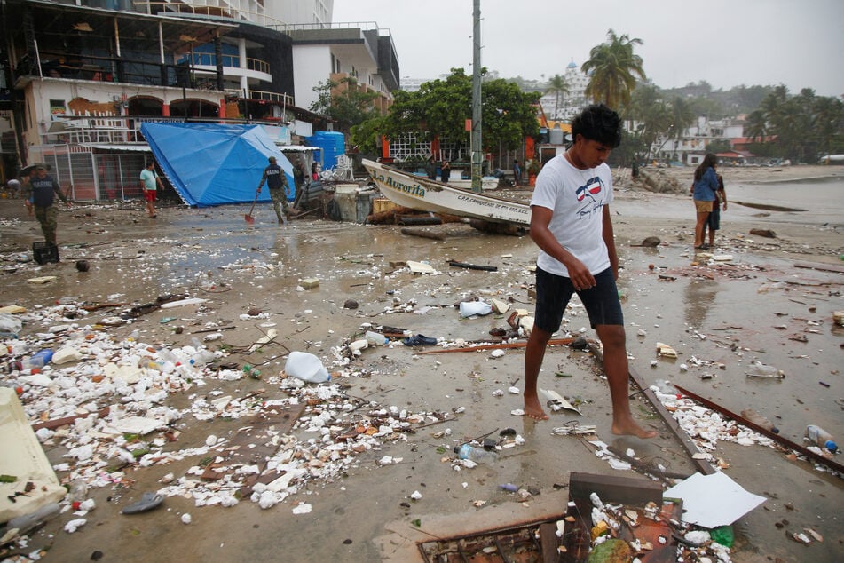 People assess damage on the beach after Hurricane Erick made landfall on the Pacific coast, in Puerto Escondido, Mexico, on June 19, 2025.