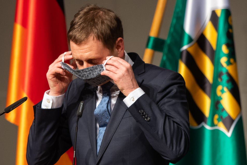 Michael Kretschmer (CDU), Ministerpräsident von Sachsen, zieht nach seiner Rede in der Sondersitzung des Sächsischen Landtages im ICC (Internationales Congress Center) seinen Mundschutz an.