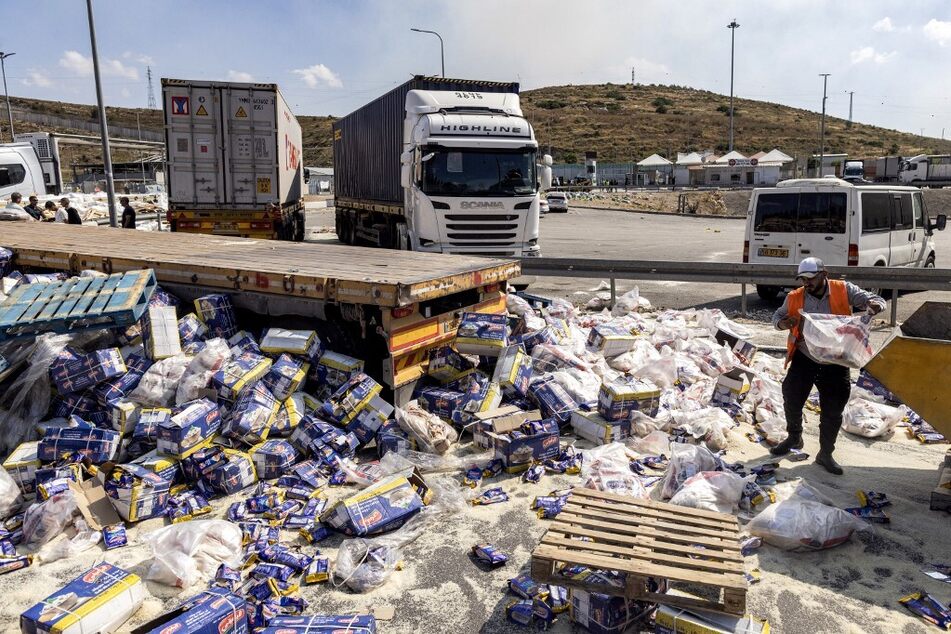 A worker clears spilled goods after settlers attacked trailer trucks carrying humanitarian aid supplies to Gaza on the Israeli side of the Tarqumiyah crossing with the occupied West Bank.