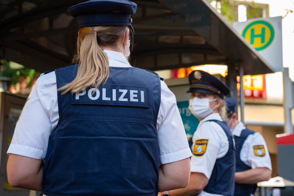 Drei Polizisten stehen an einer Haltestelle zur Maskenkontrolle.