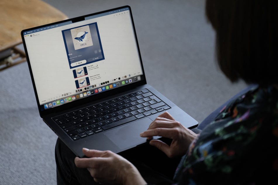 Folk singer Emily Portman poses for a photograph holding a laptop displaying a screenshot of a counterfeit album falsely claiming to be created by her in Sheffield, northern England.