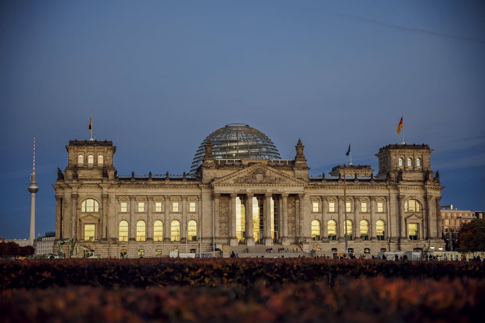 In den Scheiben des Reichstagsgebäudes spiegelt sich der Abendhimmel. Den Status als Abgeordneter gibt es für die erfolgreichen Kandidaten erst mit der Konstituierung des 21. Deutschen Bundestages. Sie muss laut Grundgesetz spätestens 30 Tage nach der Bundestagswahl erfolgen, also bis einschließlich 25. März 2025.