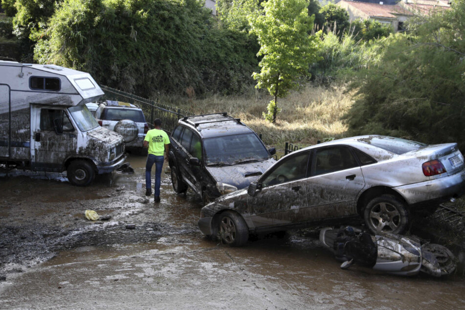 Frankreich, Ajaccio: Ein Mann geht zwischen Autos hindurch, die durch eine Überschwemmung in Folge starken Regens weggespült wurden.