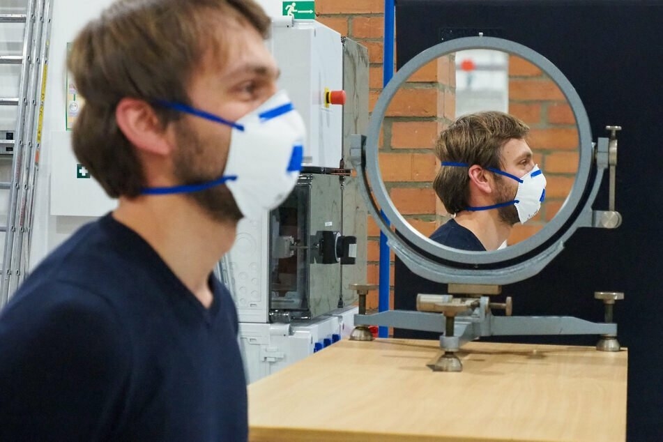 TU-Freiberg-Mitarbeiter Emanuel Thom testet die Wirksamkeit einer Maske vor einem Schlierenspiegel, durch den Aerosole sichtbar gemacht werden.