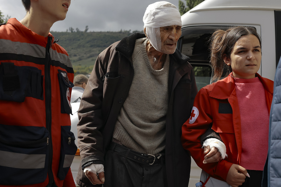 Ein verwundeter armenischer Mann namens Sasha (84) aus Stepanakert in Berg-Karabach wird von Freiwilligen bei seiner Ankunft in der armenischen Stadt Goris in der Region Syunik gestützt.