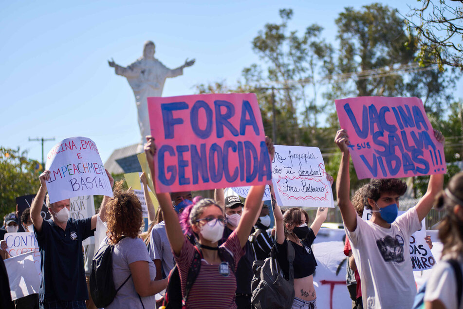 Demonstranten halten bei einem Protest Plakate auf denen Impfungen und die Absetzung von Präsident Bolsonaro gefordert wird.