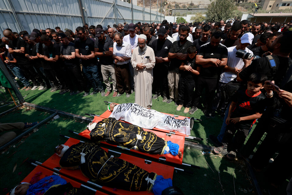 Relatives pray over the bodies of Palestinians the morning after they were killed in an Israeli air strike on the Nur Shams refugee camp on Monday.