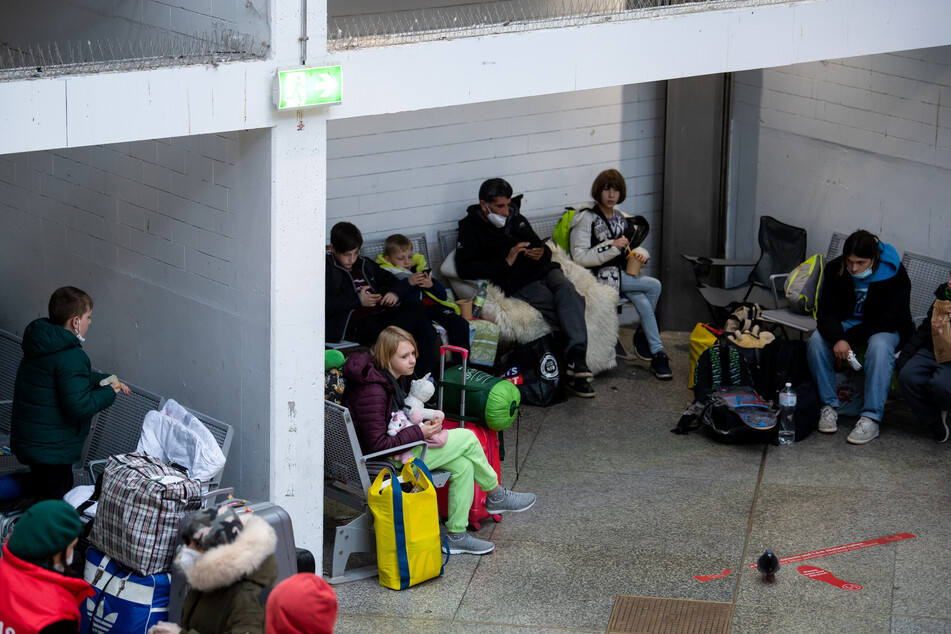 Flüchtlinge aus der Ukraine warten nach ihrer Ankunft am Hauptbahnhof in München in einer Halle.