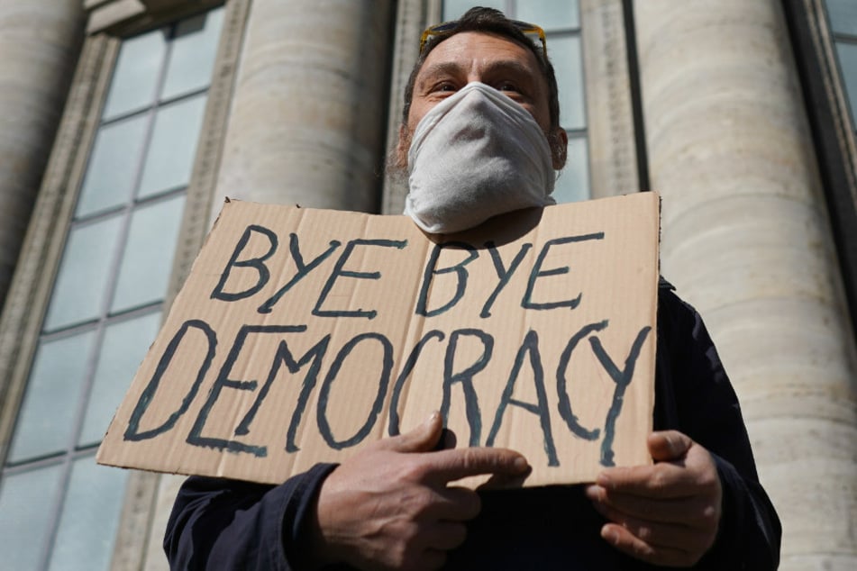 Ein Transparente mit der Aufschrift "Bye bye Democracy" wird bei einer Demonstration unter dem Motto "Grundrechte verteidigen - Sage NEIN zur Diktatur!" auf dem Rosa-Luxemburg-Platz in die Höhe gehalten. (Symbolbild)