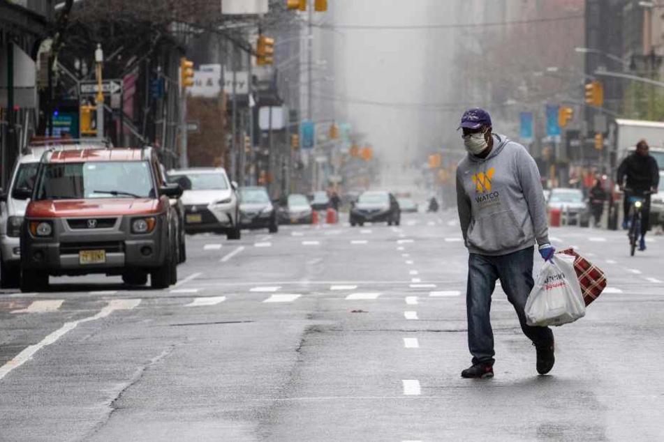 USA, New York (29. März): Ein Mann trägt eine Maske und geht über die 5th Avenue.