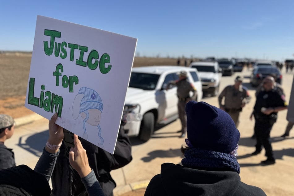 A protestor holds a "Justice for Liam" sign during a demonstration and vigil outside the South Texas Family Residential Center in Dilley, Texas, on January 28, 2026.