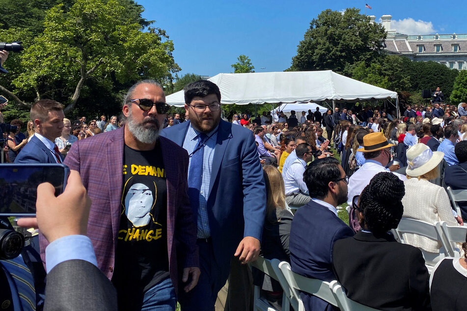 Oliver being led away from the South Lawn by a member of the security team.