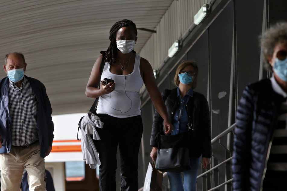 Passagiere mit Mundschutzmasken steigen in Lissabon von einer Fähre aus. (Archivbild)