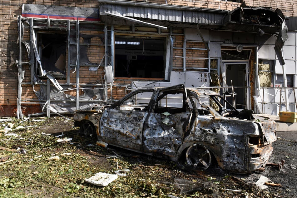 Ein verbranntes Auto ist in Kursk vor einem Wohnhaus zu sehen, das nach dem Beschuss durch die ukrainische Seite beschädigt wurde.