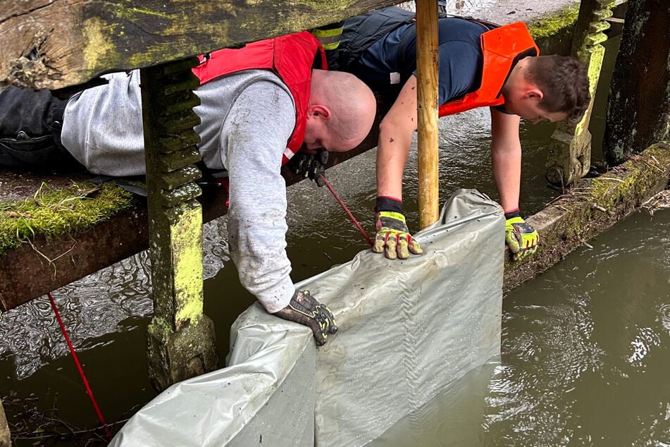 Als erste Maßnahme brachten die Feuerwehrleute mit Folie verkleidete Paletten an das Wehr ein.