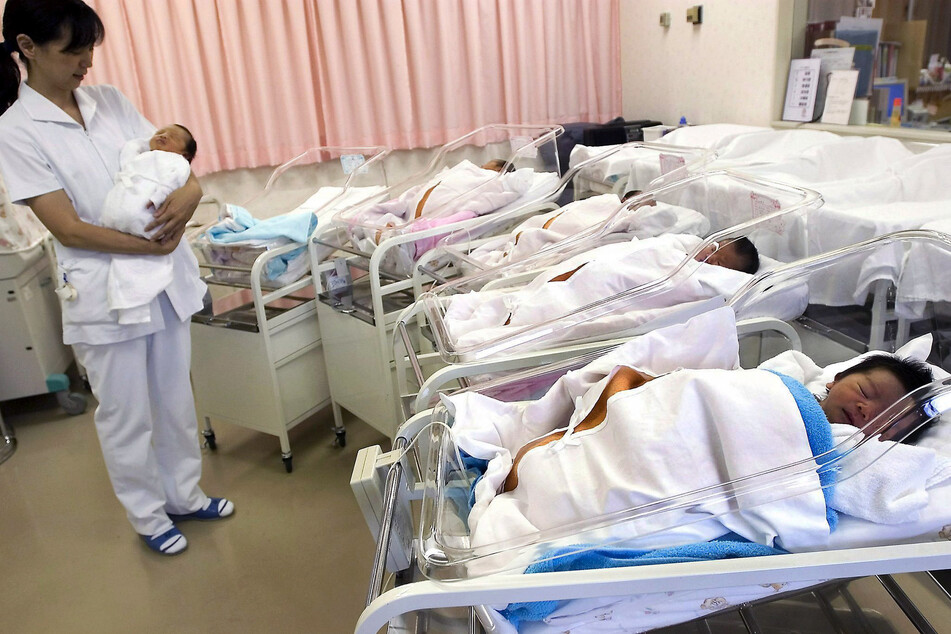 Japan, Tokio: Eine Krankenschwester hält auf einer Neugeborenenstation eines Krankenhauses ein Baby im Arm.