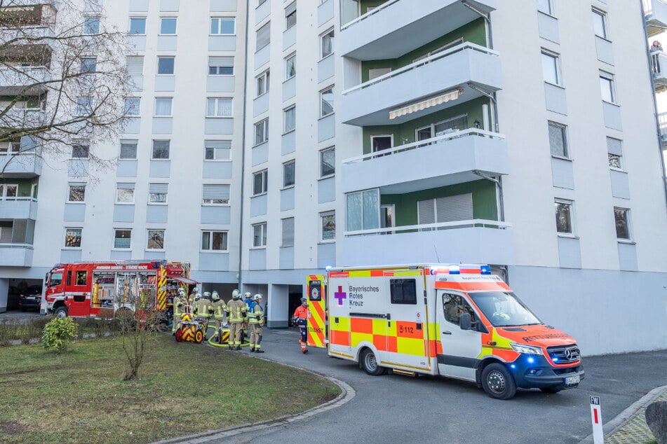 Einsatzkräfte stehen vor dem Haus in der Seewiesenstraße. Dort hat es im siebten Stock gebrannt.