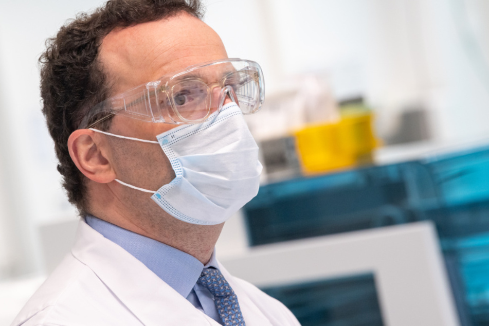 Jens Spahn (CDU) sitzt während eines Besuchs mit Mundschutz und Schutzbrille im Roche-Entwicklungslabor für den neuen serologischen Antikörpertest Elecsys Anti-SARS-CoV-2.