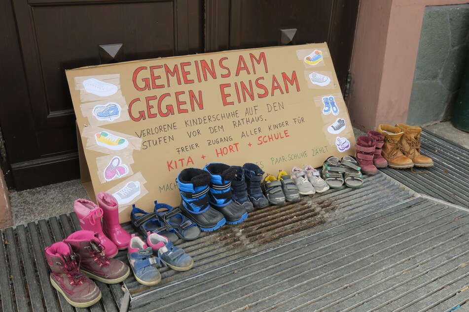 Vor dem Rathaus in Aue stellten Eltern die Schuhe ihrer Kinder ab - dazu ein Plakat. Sie protestieren damit gegen die geplanten Kita- und Schulschließungen am Montag.