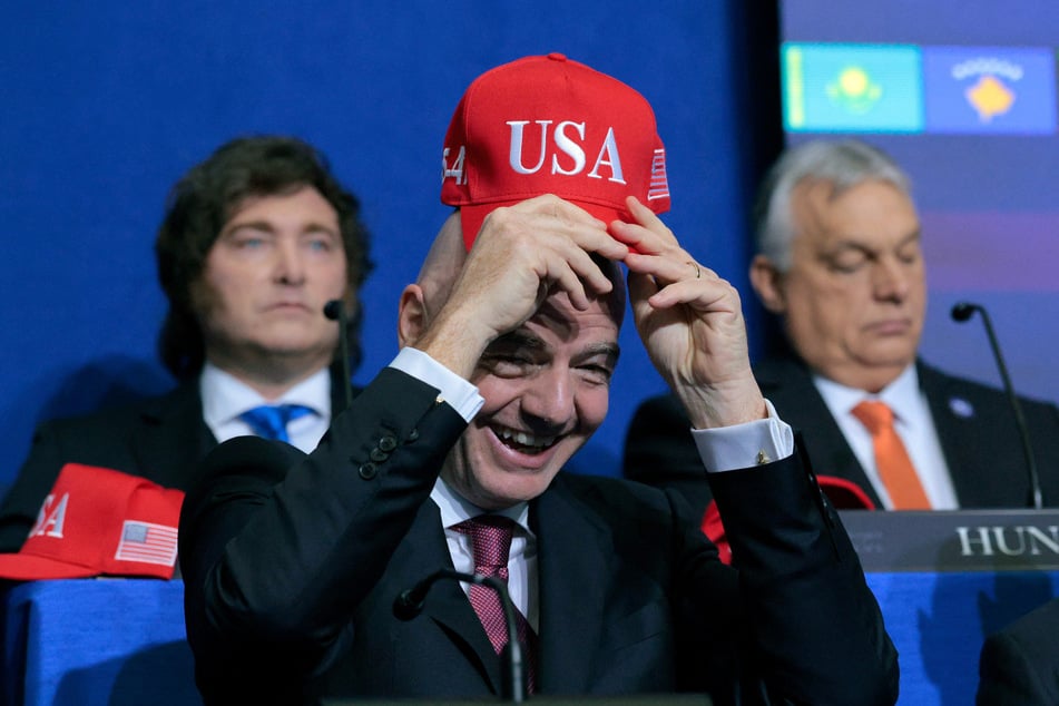 FIFA President Gianni Infantino holds up a USA hat as he attends the inaugural meeting of the Board of Peace in Washington DC on February 19, 2026.