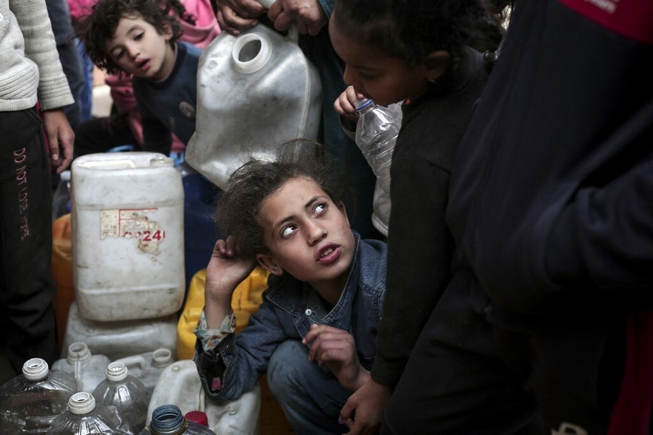 Palestinian children gather around containers of water in Rafah in the southern Gaza Strip on March 1, 2024.