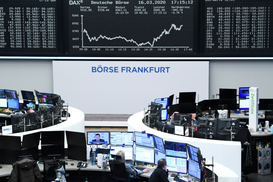 Aktienhändler arbeiten im Handelssaal der Frankfurter Wertpapierbörse vor der Anzeigetafel mit der Dax-Kurve.