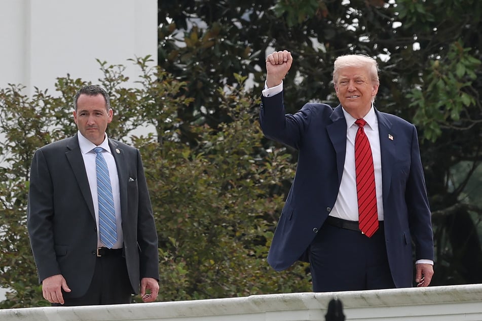 President Donald Trump gestures from the roof of the West Wing of the White House as he takes a tour on August 5, 2025.