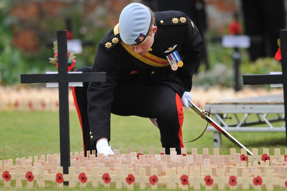 Britain's Prince Harry lays a cross of remembrance in memory of his friend Lance Corporal of Horse, Jonathan Woodgate, from the Household Cavalry, during a ceremony to open the first remembrance field dedicated solely to British military personnel killed in Afghanistan since 2001 on November 9, 2010.