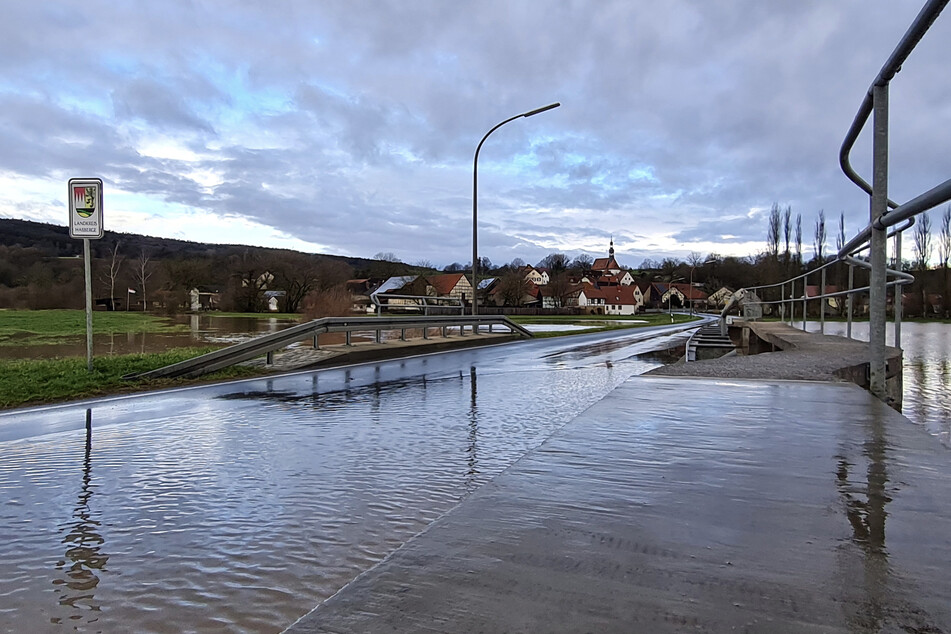 Die Straße zwischen Gleusdorf (Gemeinde Untermerzbach, Landkreis Haßberge, Unterfranken) und Busendorf (Gemeinde Rattelsdorf, Landkreis Bamberg, Oberfranken) wurde überschwemmt. Im Hintergrund ist der Ort Gleusdorf zu sehen.
